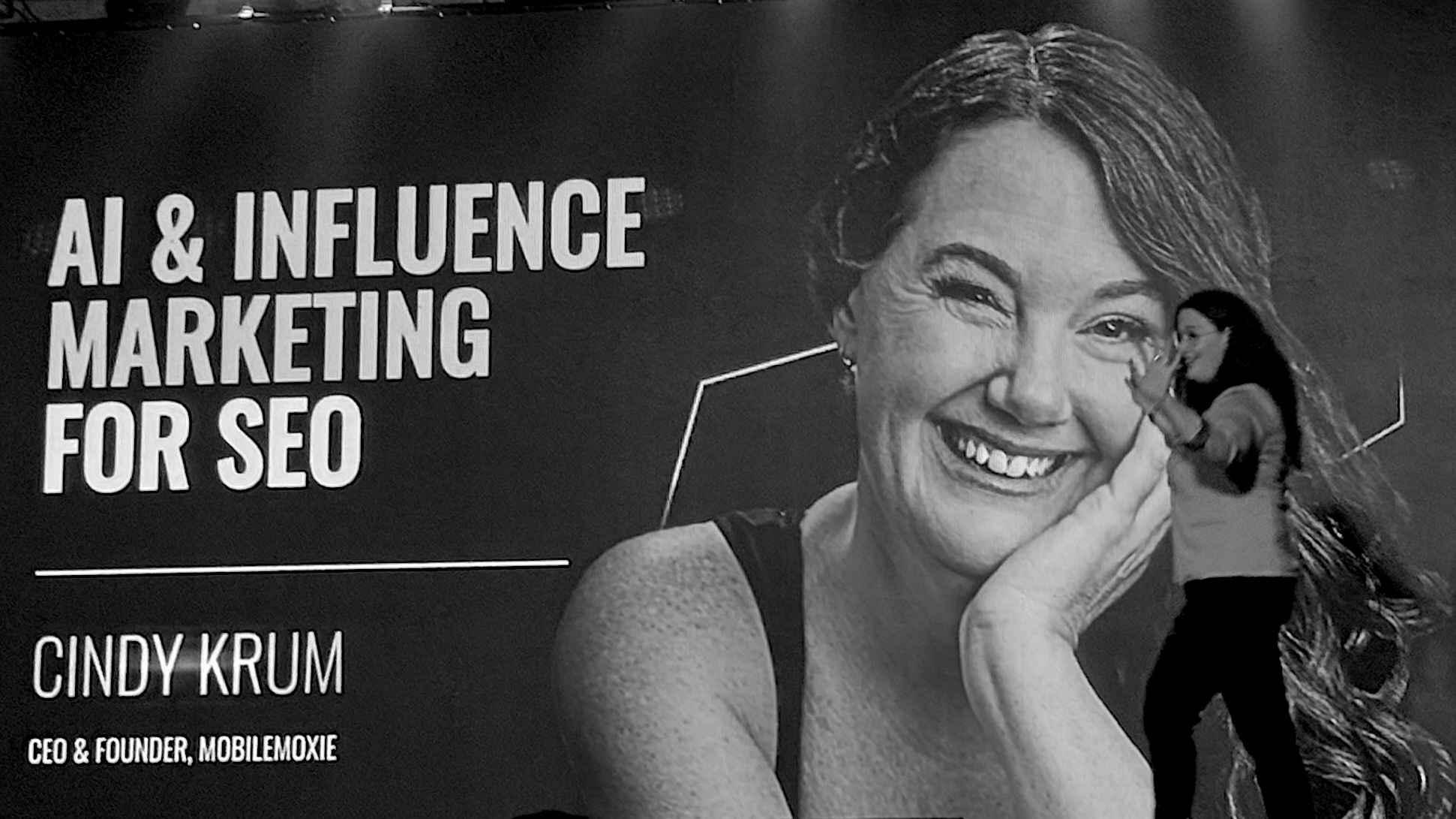 A dynamic black-and-white photo of a speaker presenting on AI and influencer marketing for SEO at a digital marketing conference.