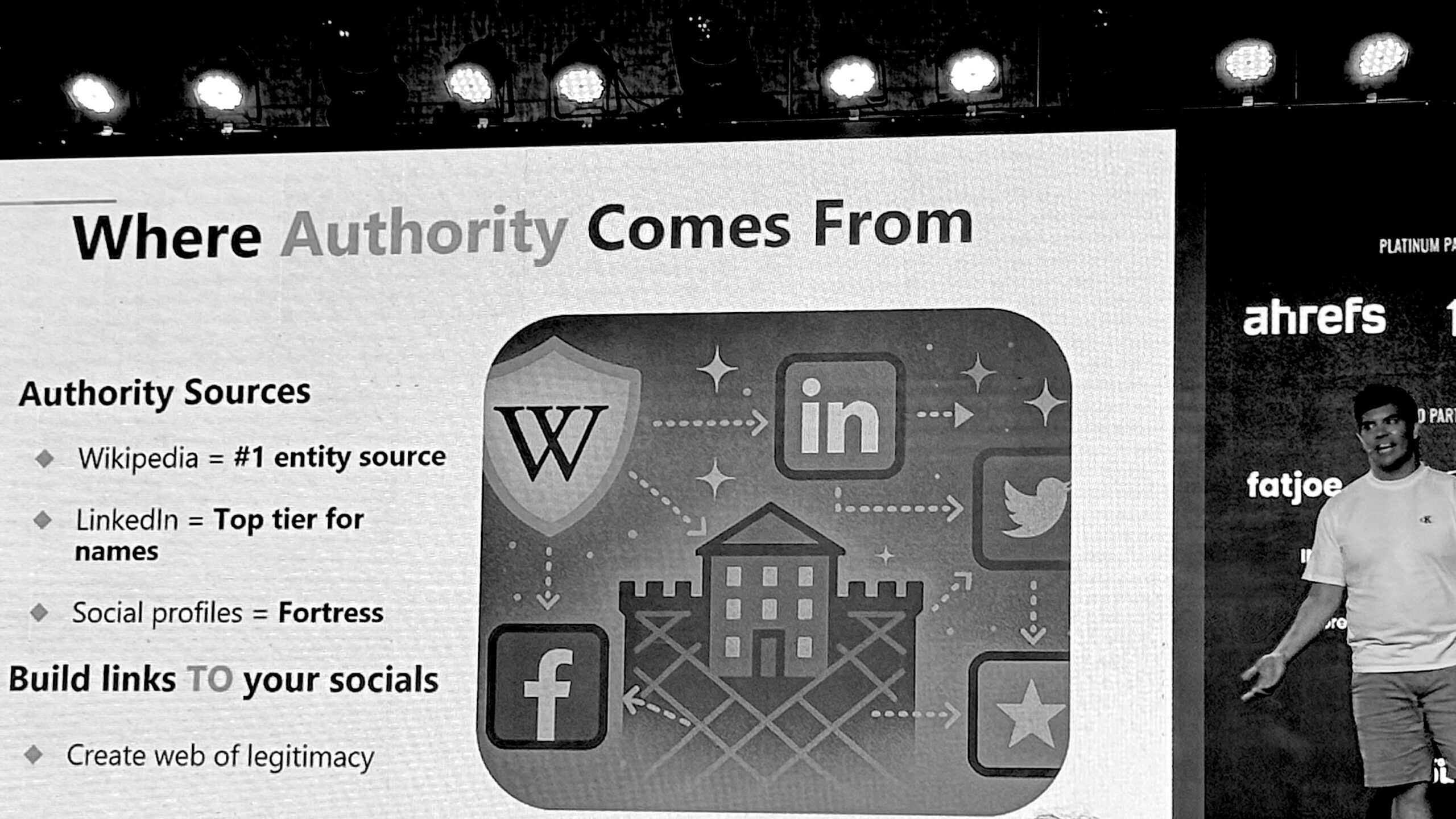 Speaker presents a digital marketing slide on building online authority through Wikipedia, LinkedIn, and social profiles at an SEO conference.