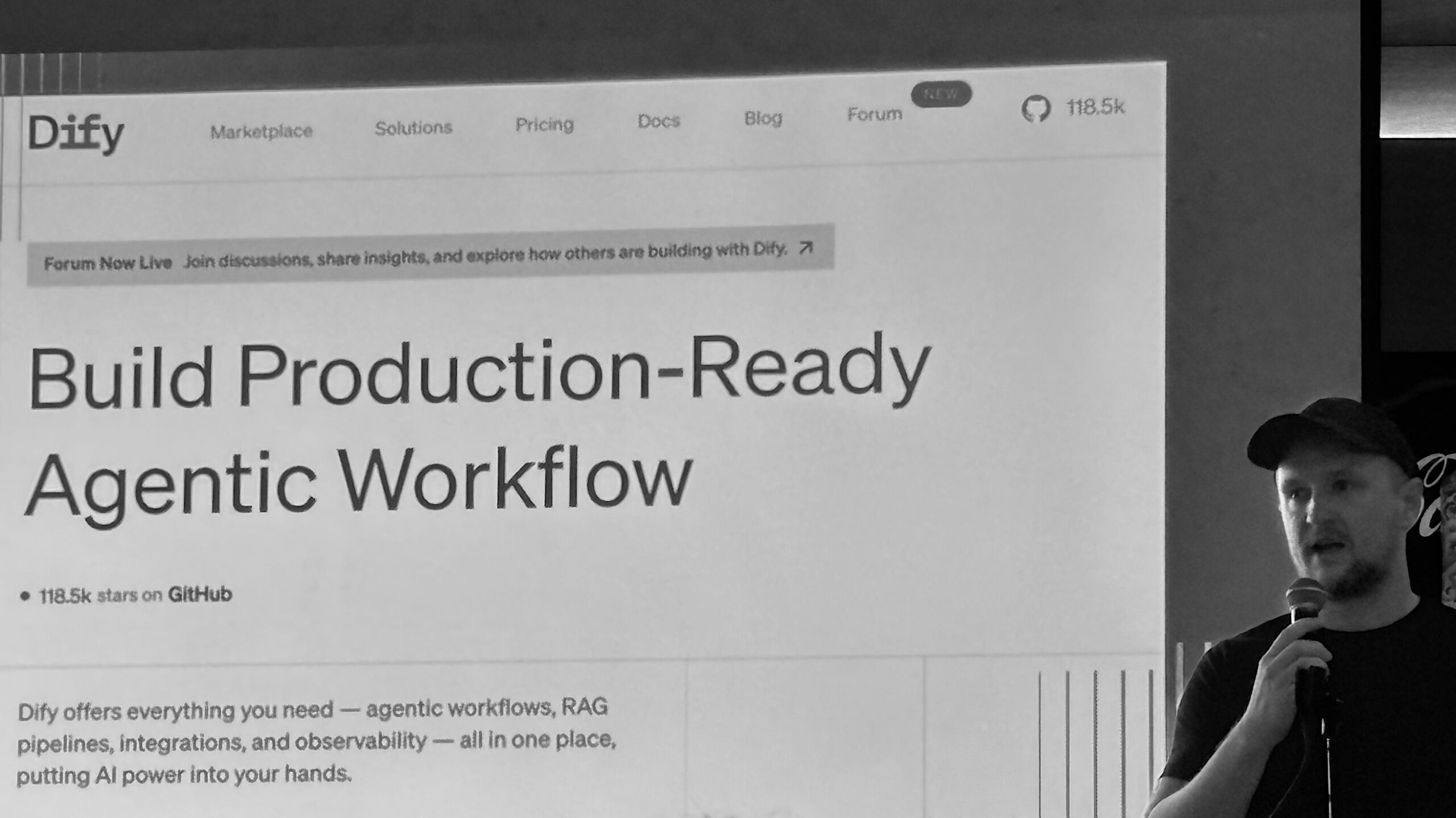 A presenter speaks next to a large projected slide showcasing Dify's platform for building production-ready agentic workflows with AI integration tools.
