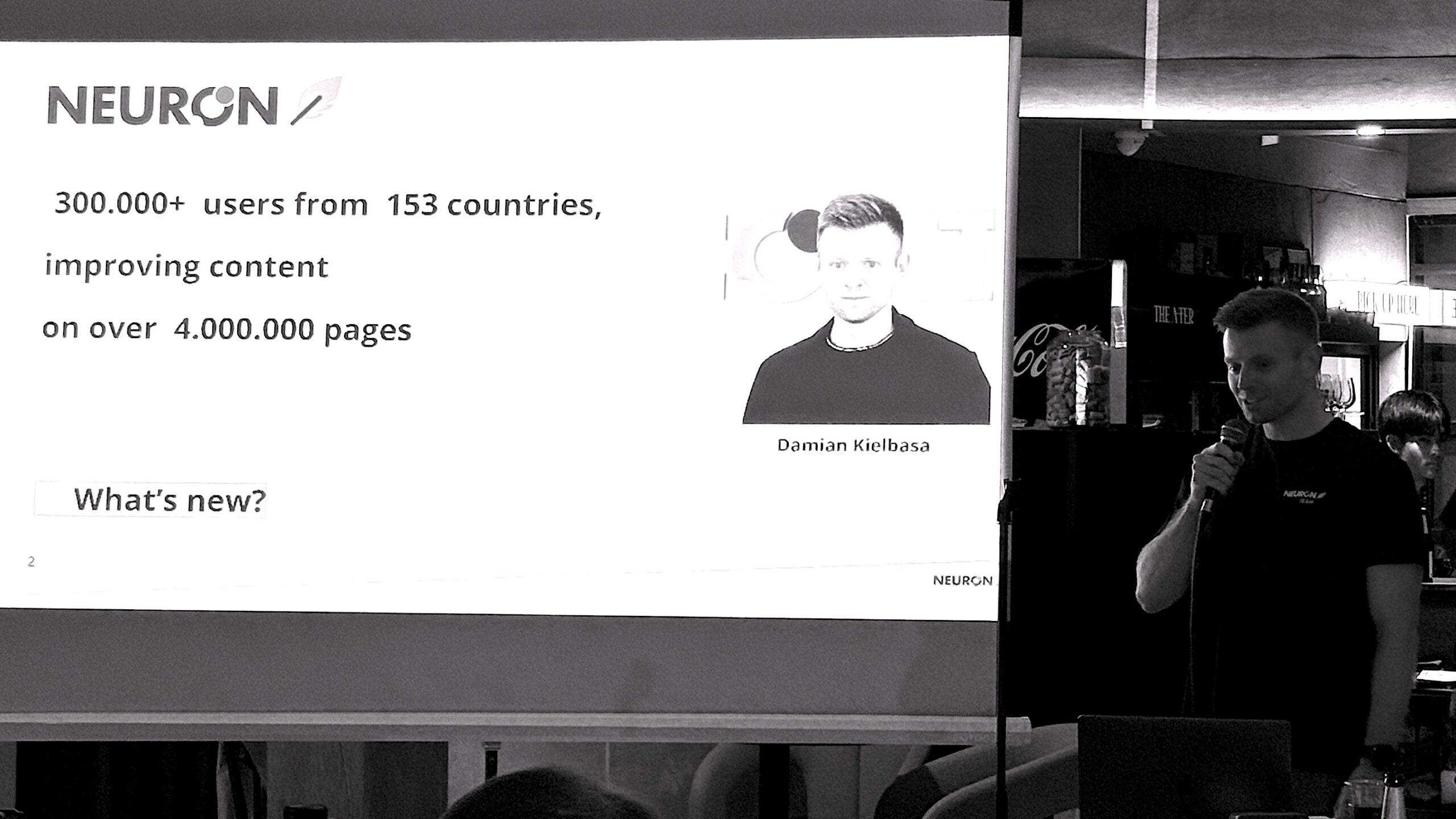 A speaker presents Neuron's global content optimization platform with over 300,000 users across 153 countries, showcasing impressive scalability and marketing reach.